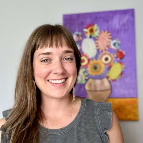 Leanne Morton, a Kaiser Therapist, stands in front of colorful art in Denver, Colorado.